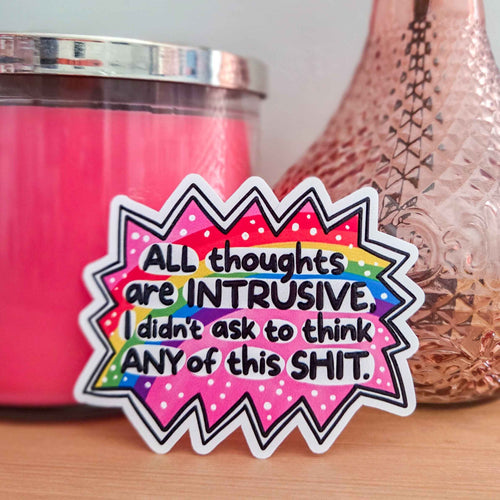 A die-cut sticker with a rainbow and pink starburst design featuring the text 'ALL thoughts are INTRUSIVE. I didn't ask to think ANY of this SHIT.'