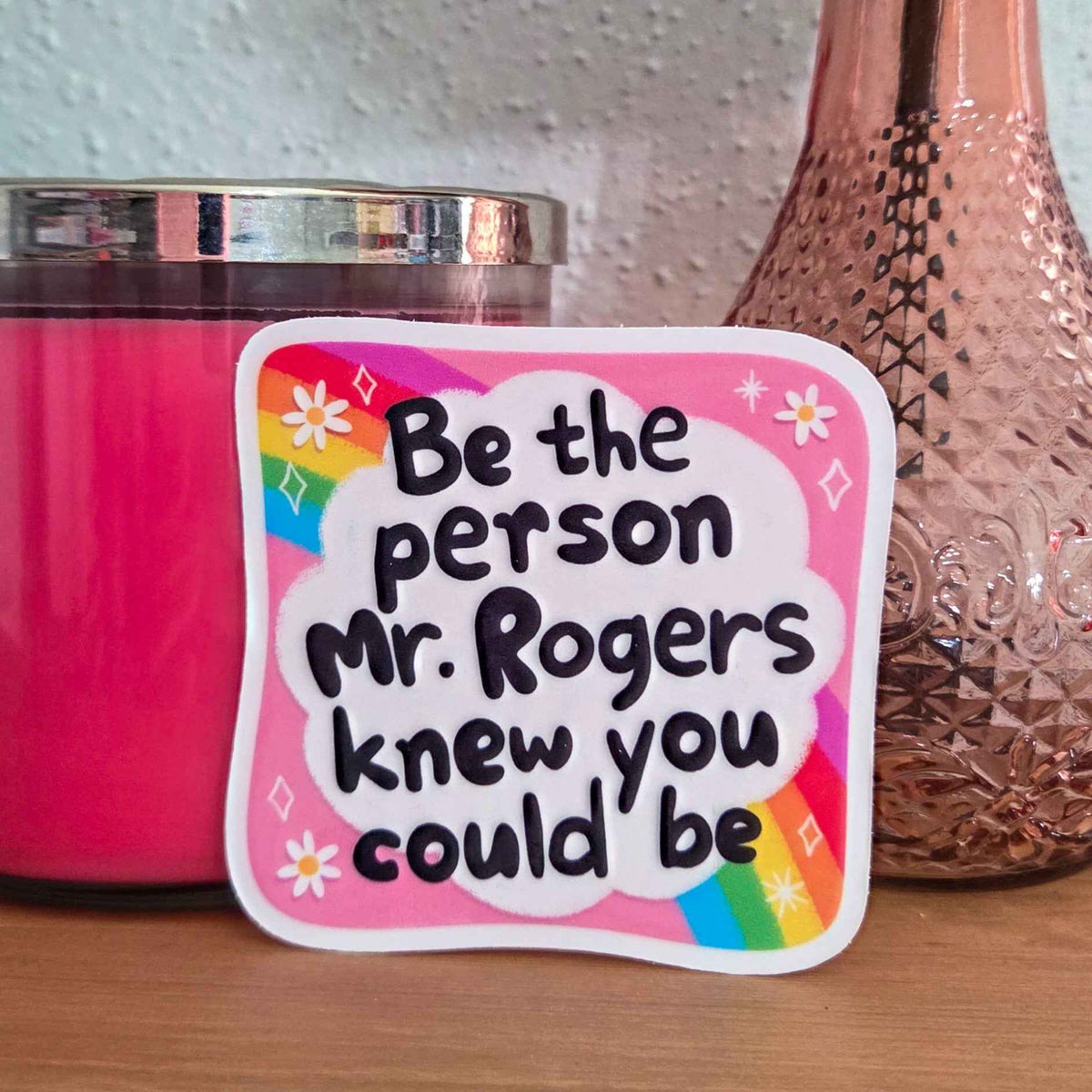 Pink candle with a motivational sticker on a wooden surface