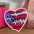 Heart-shaped sticker with motivational quote on a surface with a vase and candle in the background