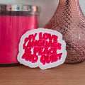 A die-cut sticker with a colorful design that reads ‘My Love Language Is Peace and Quiet' resting on a wooden surface.