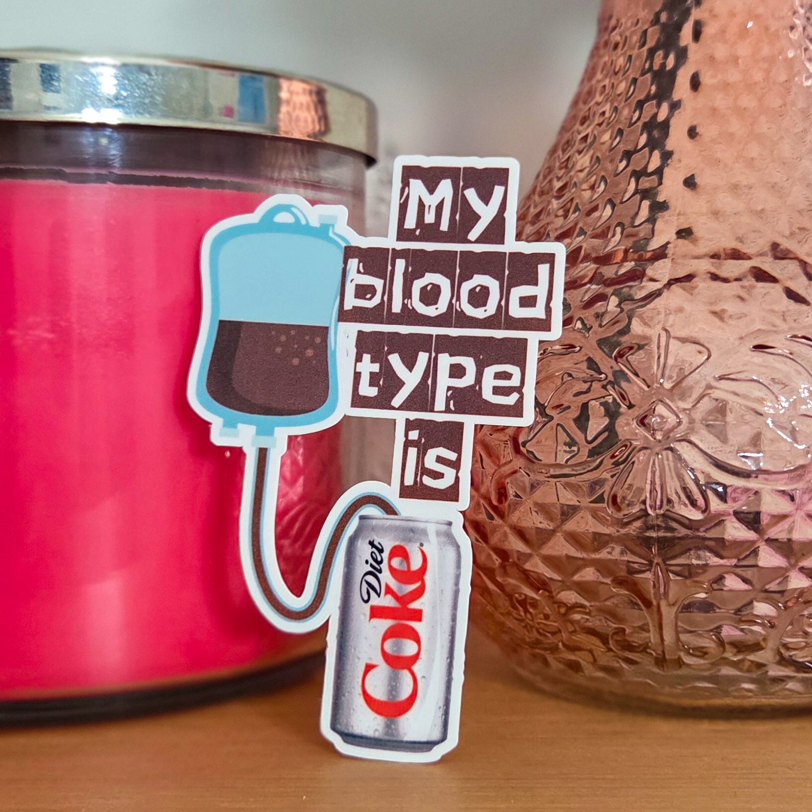 Pink candle and decorative vase on a wooden surface with a humorous text overlay.