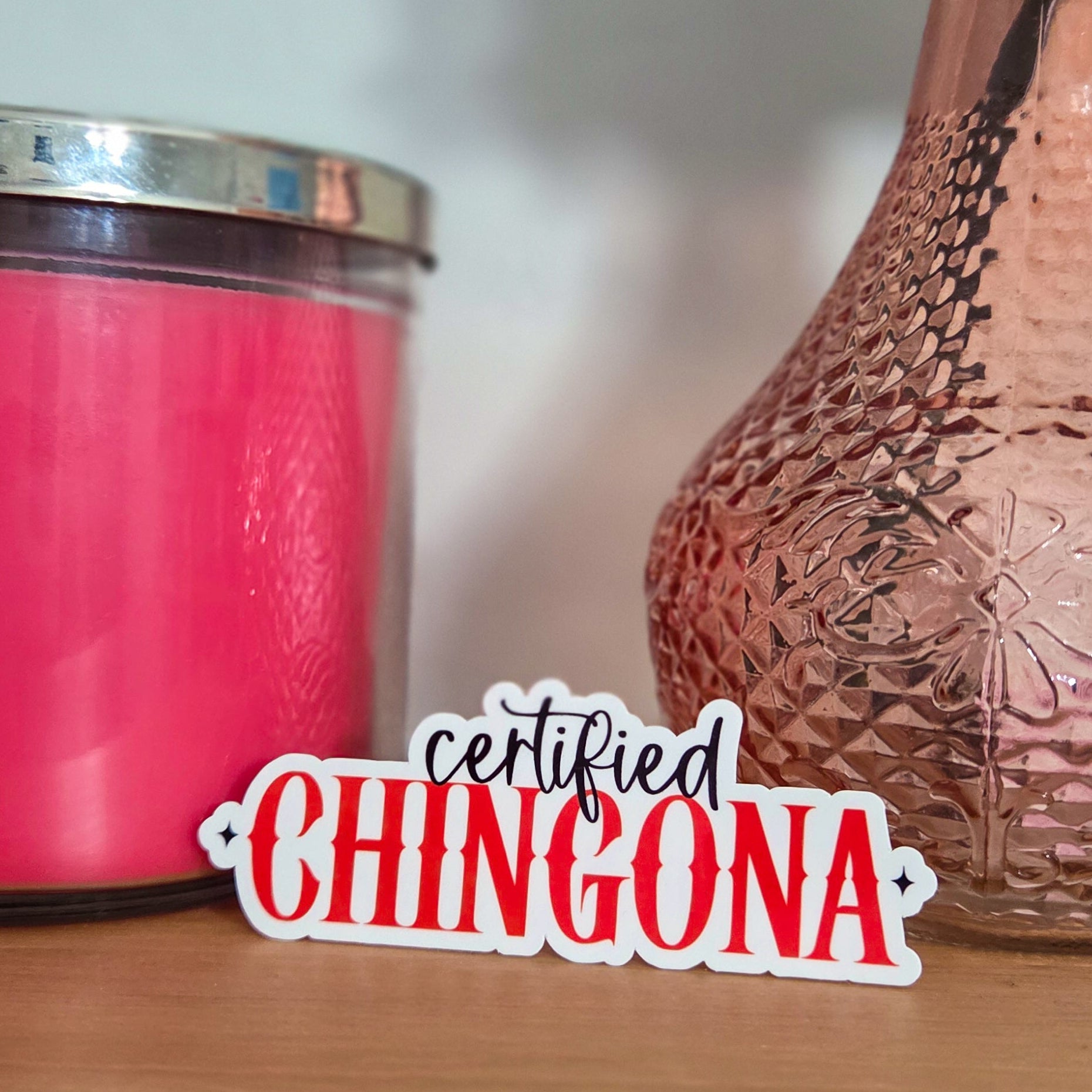 Pink candle and textured vase on a wooden surface with 'certified CHINGONA' text overlay.