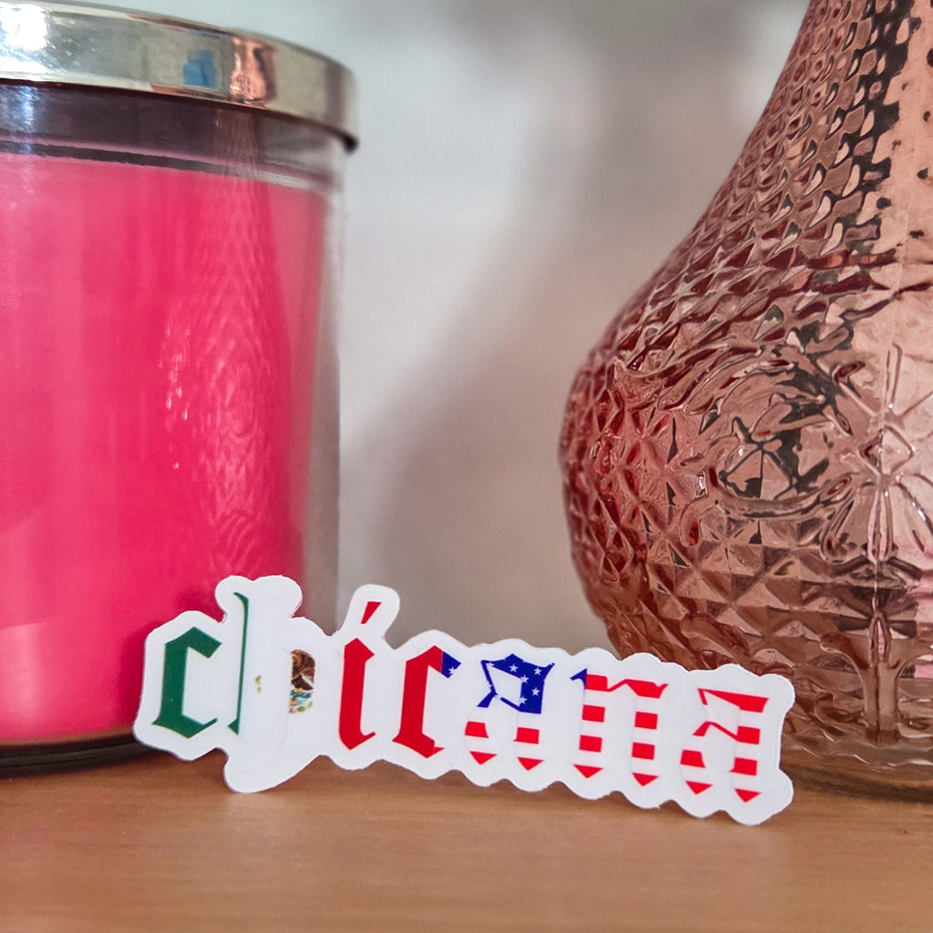 Pink candle and textured vase on a wooden surface with a blurred 'Chicana' logo.