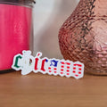 Pink textured vase and pink candle on a wooden surface with a decorative sticker.