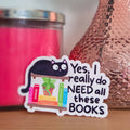 Pink candle, textured vase with a rose, and a sticker on a wooden surface.