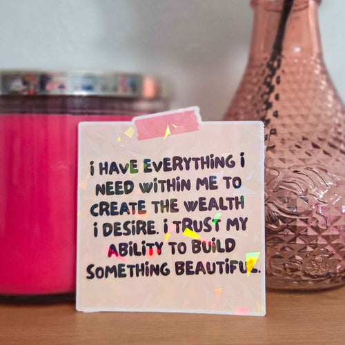 Motivational sticker with affirmation on a wooden surface with decorative items.
