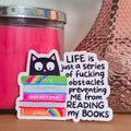 Sticker with text on a surface with a pink candle and vase in the background