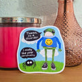 Sticker with a cartoon character and text on a pink candle and vase with flowers.