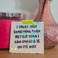 Motivational sticker with a quote next to a pink vase with a rose on a wooden surface.